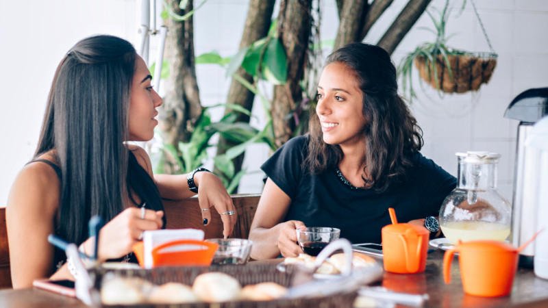 Zwei Frauen sitzen in einem Café und unterhalten sich angeregt