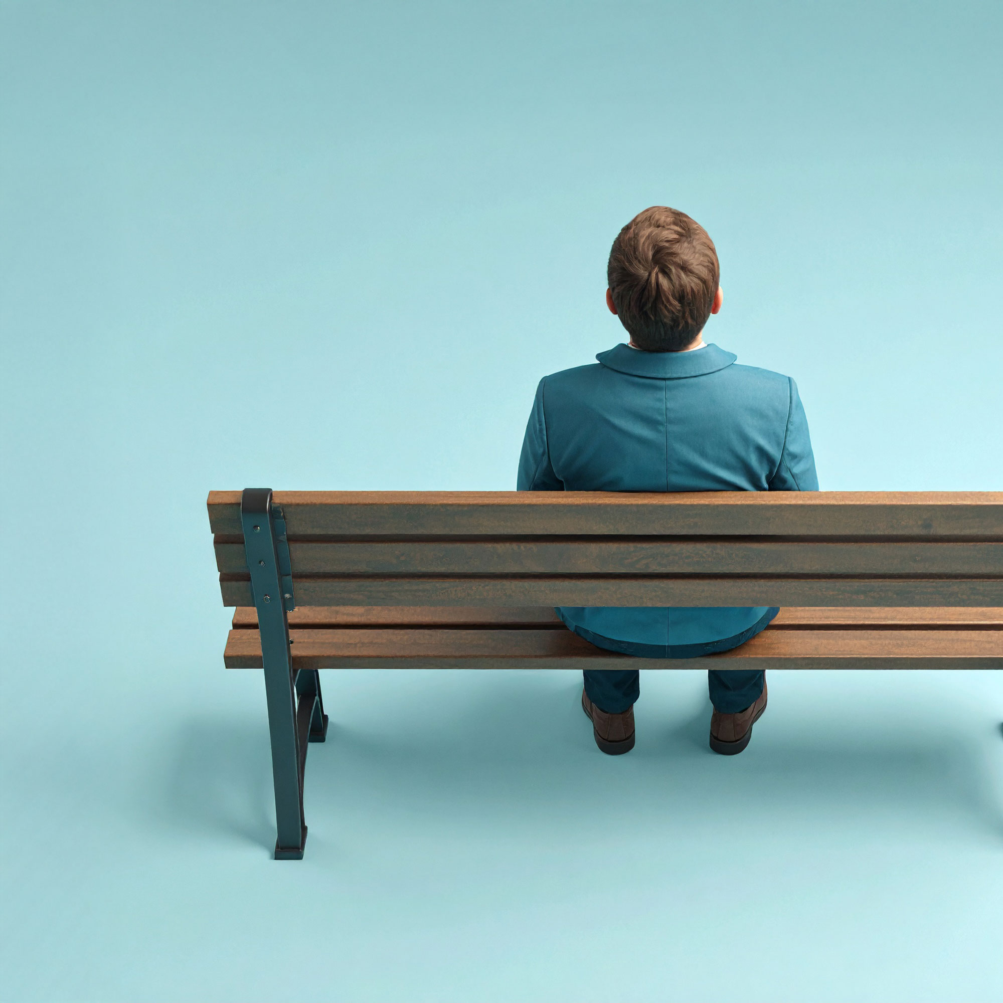 Tagung: "Einsam. Gesellschaft ohne Gemeinschaft" (© Rainer Stenzel) Eine Person ist von hinten zu sehen, wie sie alleine auf einer Bank sitzt.